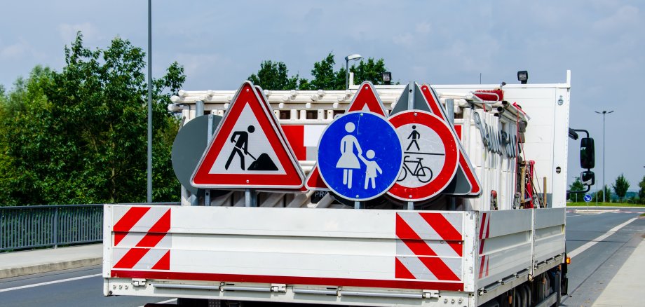 A worker's truck with roadsigns at a road construction site