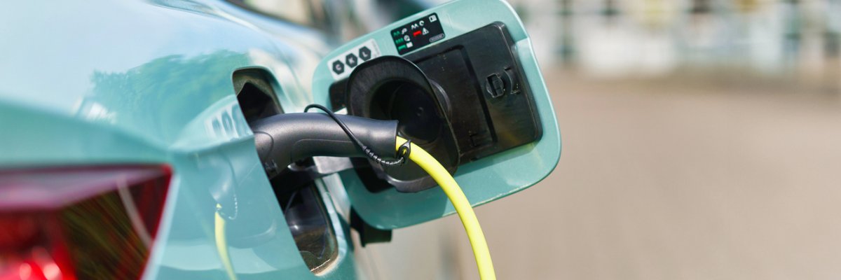 Electric car in the parking lot, connected to a charging station