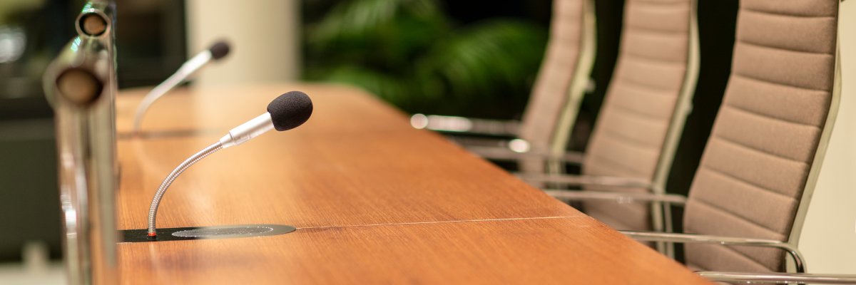 Isolated view of a microphone in the front of a conference room among blurred other mikes in the background