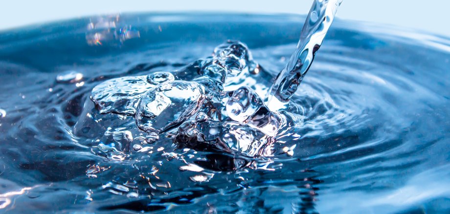 A flowing stream of blue water. Splash of water close-up. Frozen water drop photographed at high speed.Slow dripping of liquid with air bubbles. Nature backgrounds or Wallpaper.Frozen liquid splashes